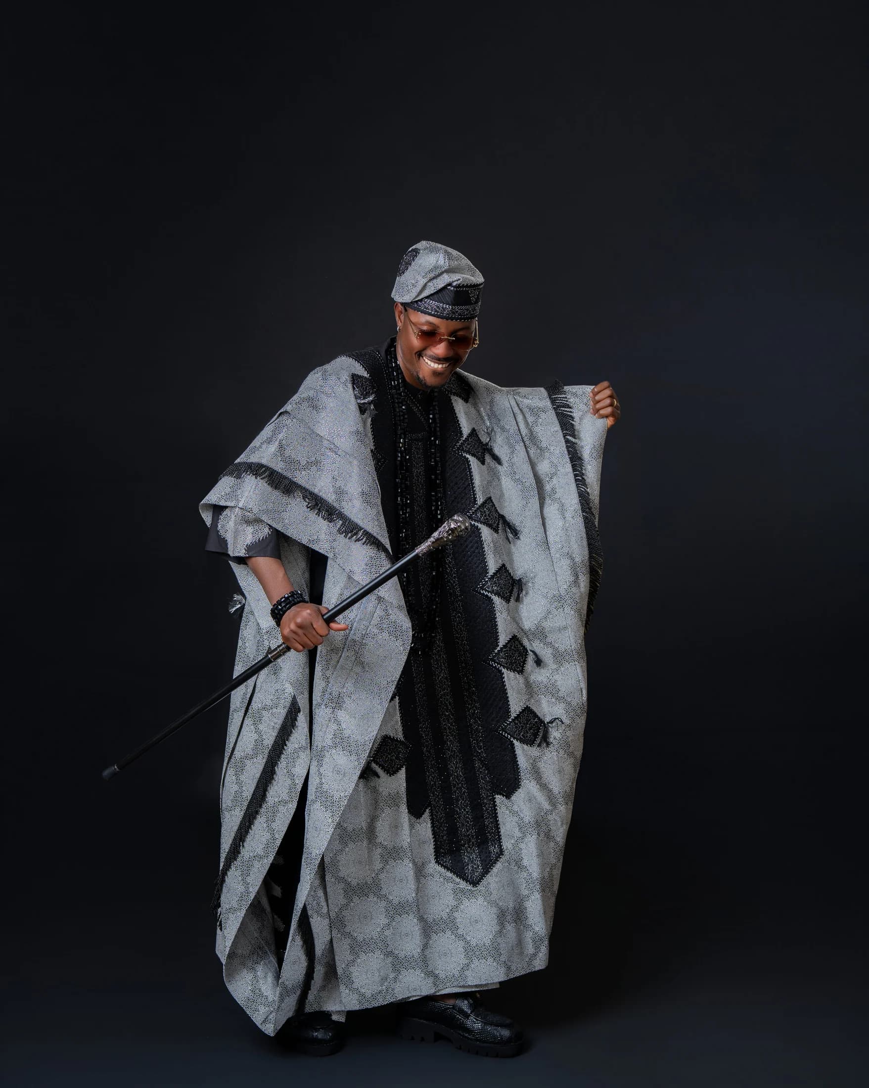Philip Akinjobi laughing while holding his flowing agbada and ceremonial walking stick
