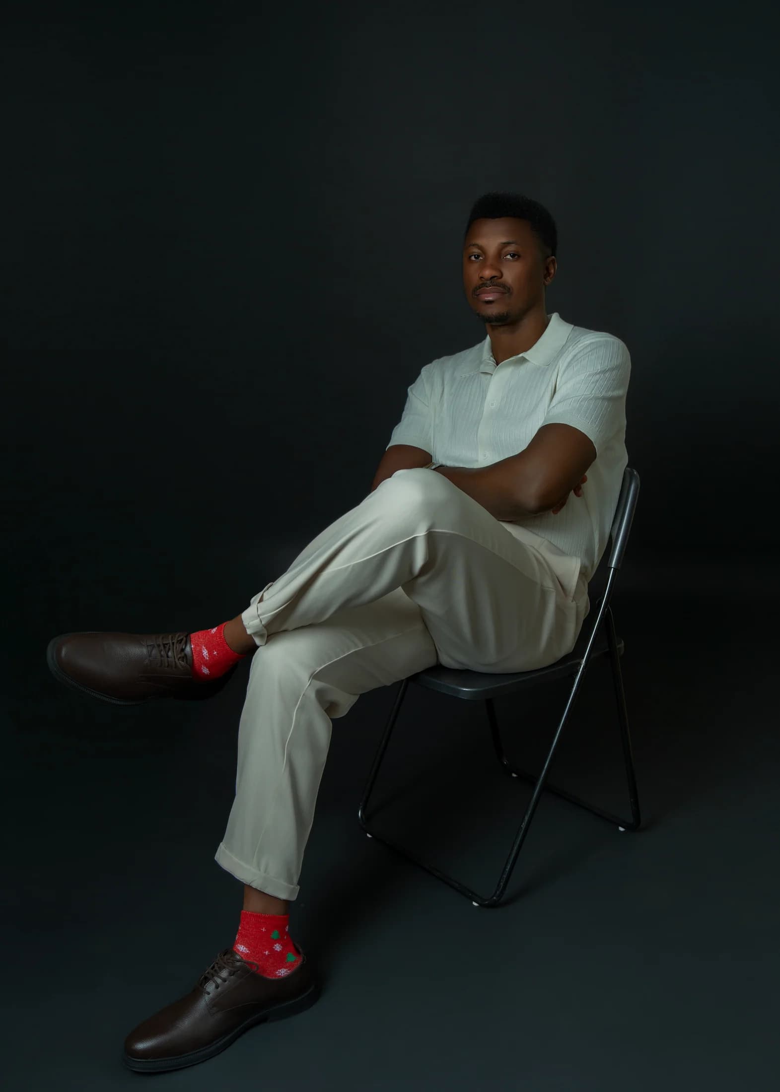 Philip Akinjobi seated with his legs crossed and arms folded in an ivory outfit