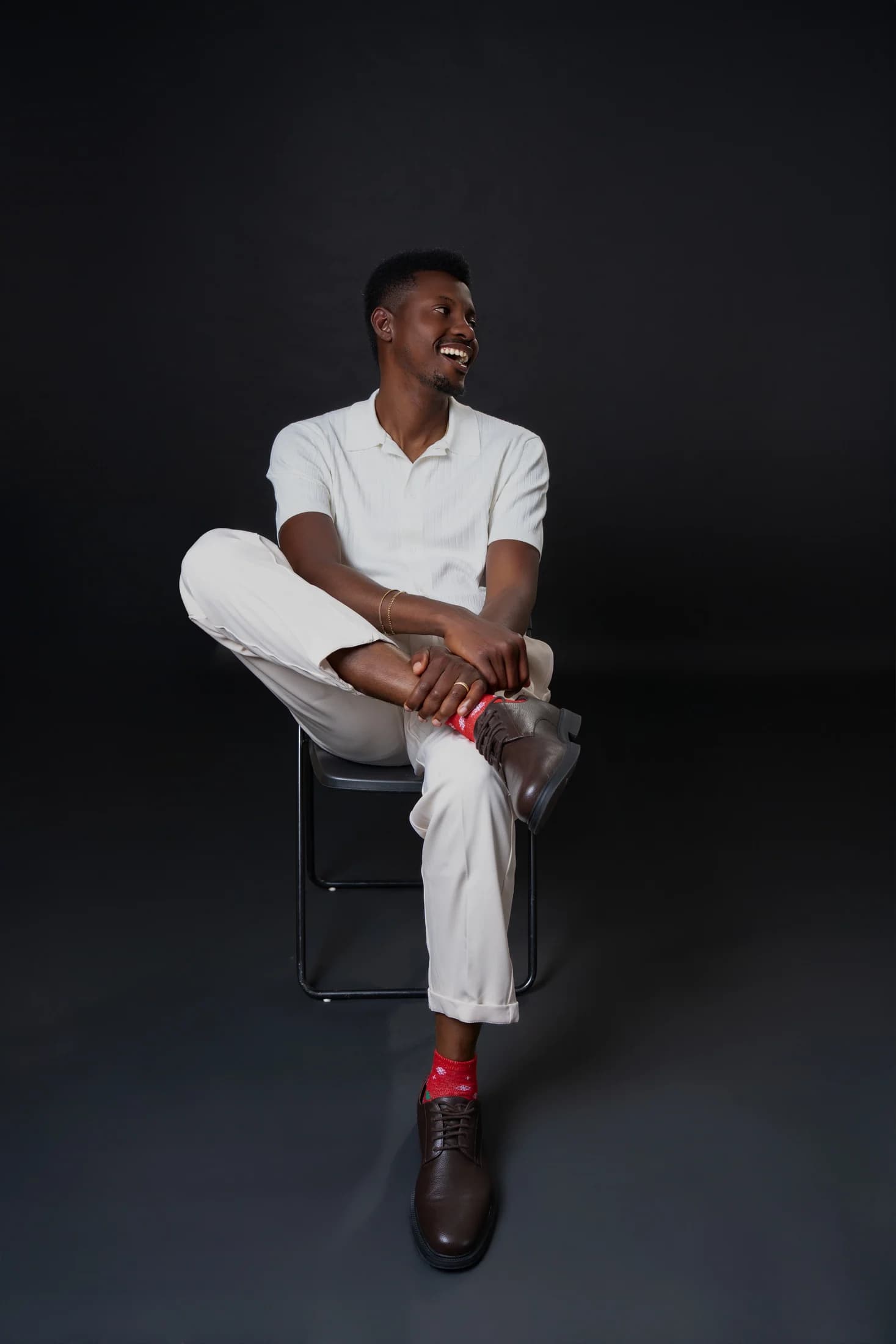 Philip Akinjobi laughing while seated in an ivory outfit